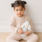 Soft gray plush bunny with white ears and face, by Snuggle Bunnies, held by child in beige knit outfit, lifestyle front view