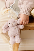 Child with stuffed rabbit toy and shiny purse.
