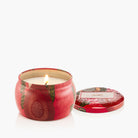 Candle in a decorative red tin with a floral design on a white background