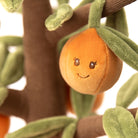 Plush toy orange with a face on a branch with leaves