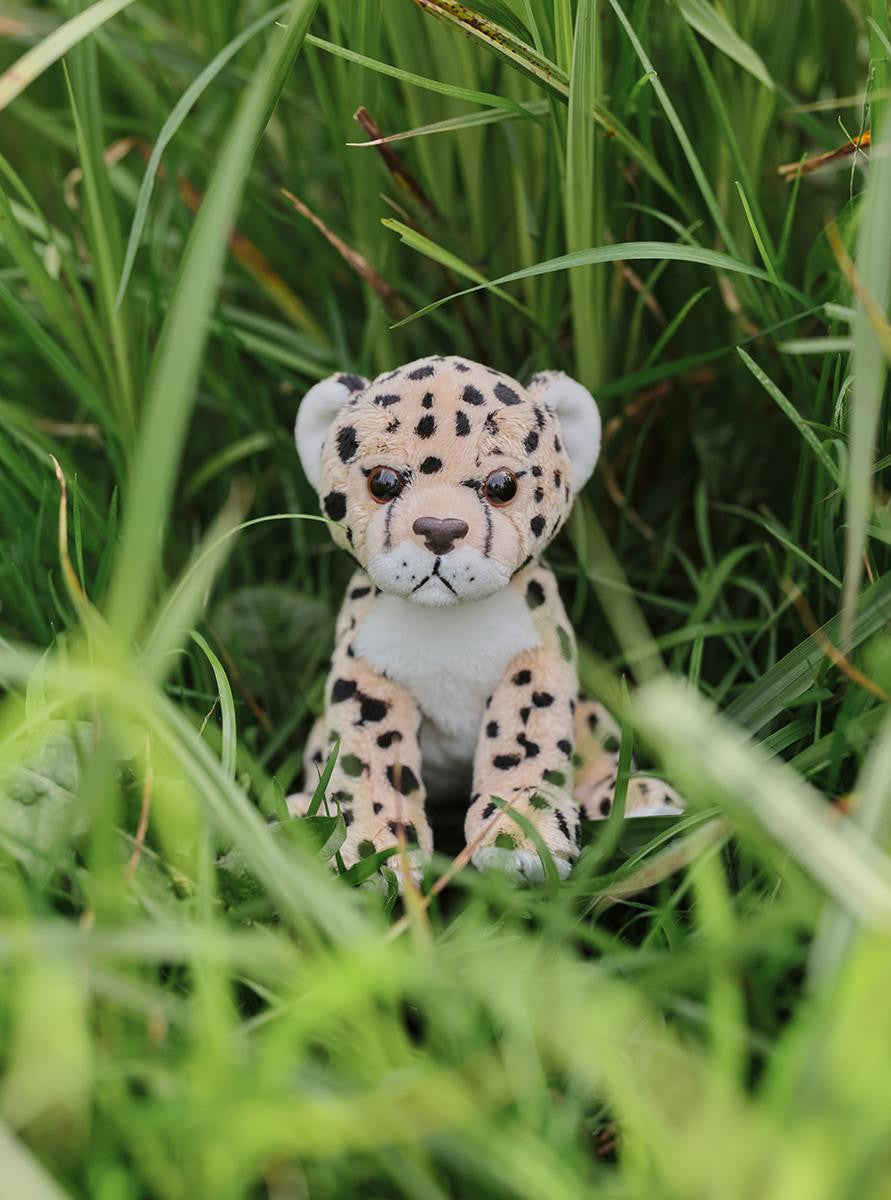Plush toy leopard sitting in a grassy area