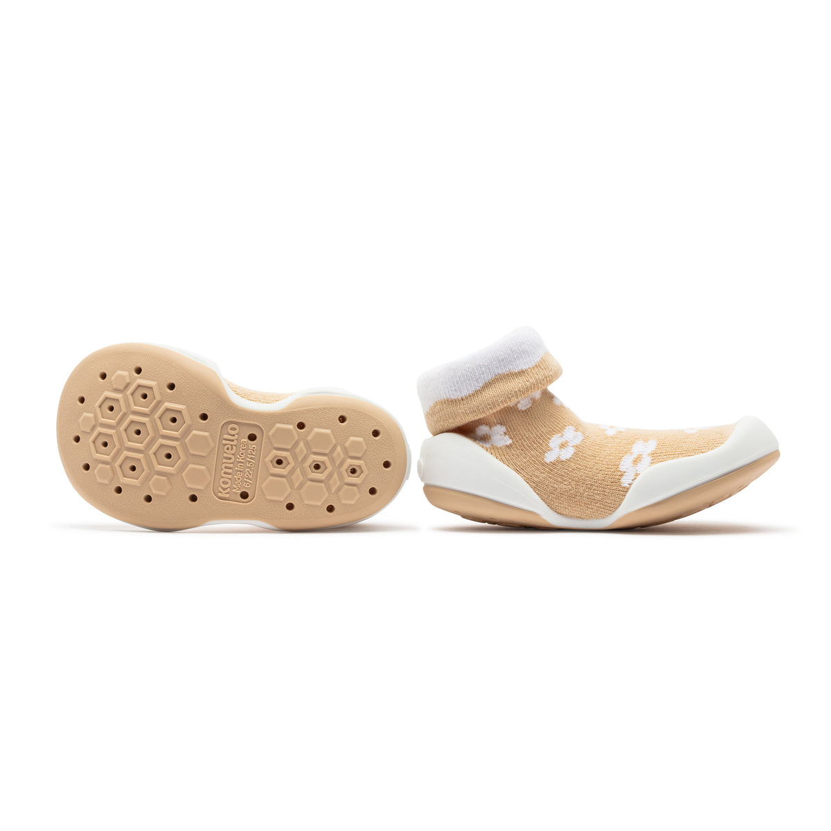 A pair of beige sock-shoes with white trim and floral pattern. 
