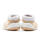 Two baby shoes with white and beige socks.