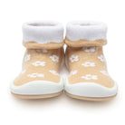 Pair of tan baby sock shoes with white cuffs and flower pattern.