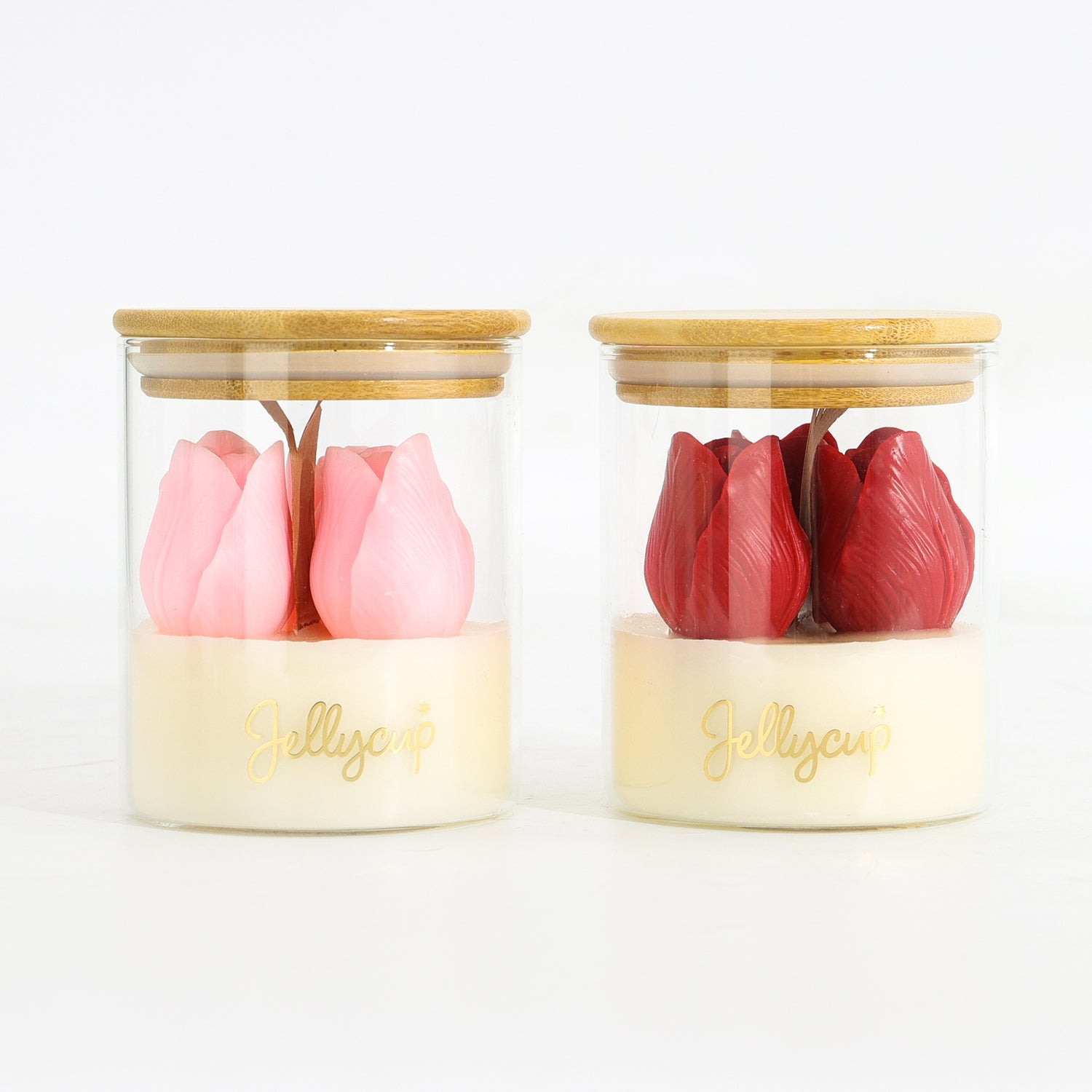 Two clear glass jars with bamboo lids and cream-colored bases, each containing a tulip-shaped jolly cup. One cup is light pink and the other is dark red, with the brand name 'Jolly cup' printed in gold on the base.