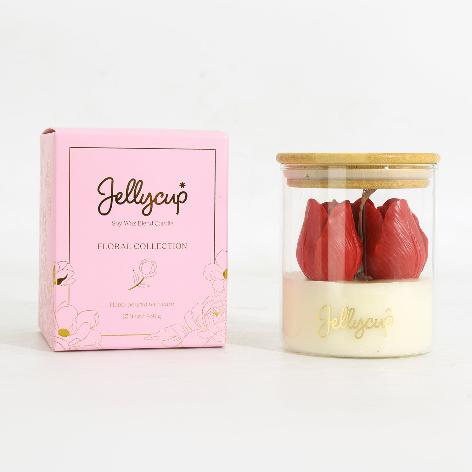 A Jellycup soy wax candle in a clear glass jar with a bamboo lid, shown next to its pink floral collection box. The candle features two red tulip-shaped wax flowers set in a creamy off-white wax base with gold foil branding.