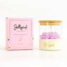 A Jellycup soy wax candle in a clear glass jar with a bamboo lid, shown next to its pink floral collection box on a white background.