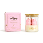 A pink Jellycup soy wax candle in a clear glass jar with a bamboo lid, shown next to its pink packaging box on a white background.