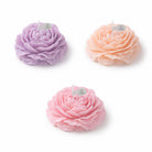 Floral peonie candles by Jellycup in light purple, peach, and pink with small flag embellishments.
