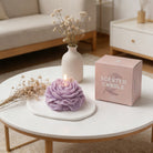 Purple Peonie candle by Jellycup sitting on a white tray with dried flowers and the candle's packaging.