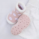 Pink and white baby shoe with flower pattern on white shorts.