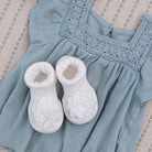 Baby blue dress with white booties on textured fabric.
