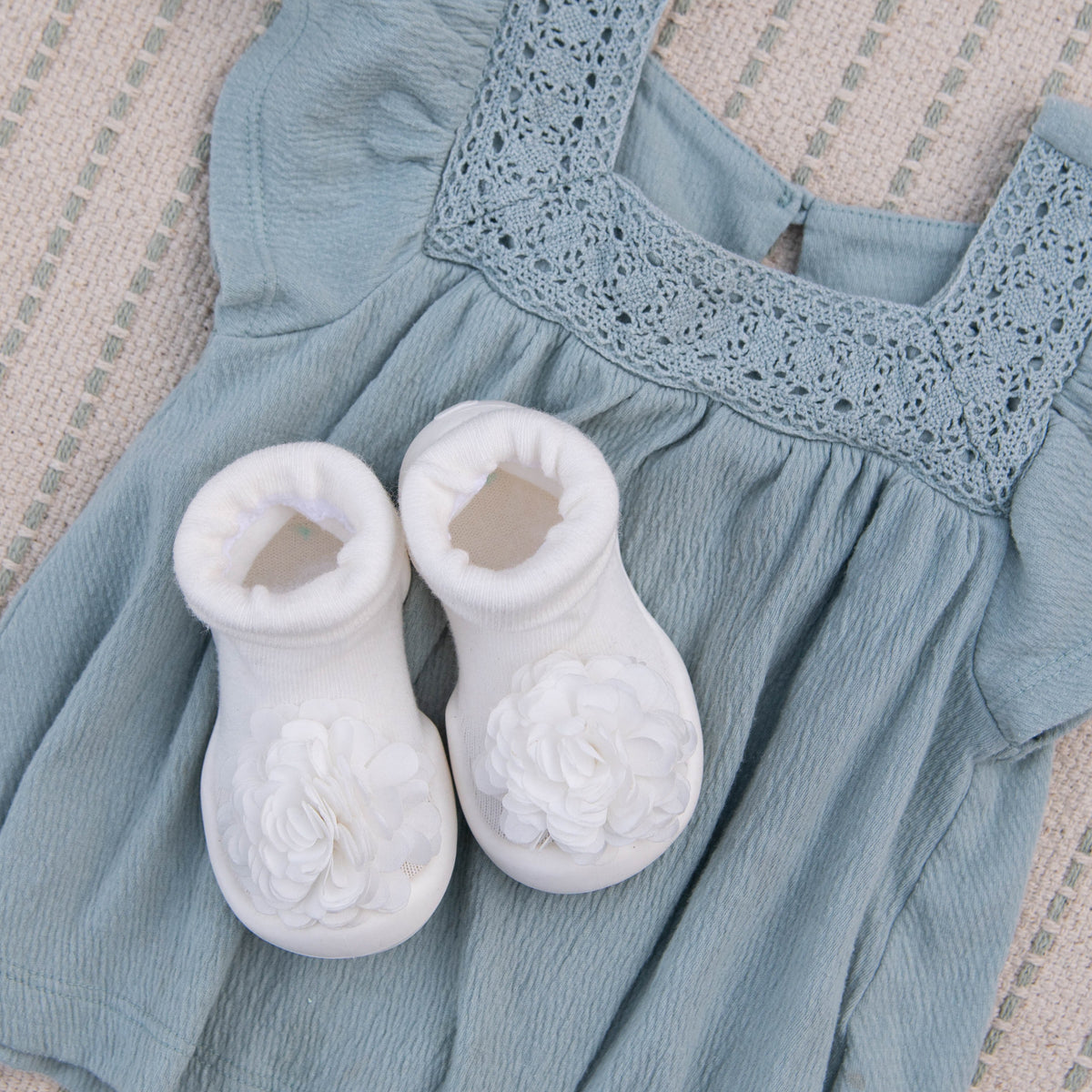 Baby blue dress with white booties on textured fabric.
