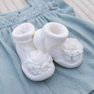 White baby booties with flower detail on blue dress.
