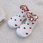 White socks with red hearts and ruffled edges on a textured beige surface