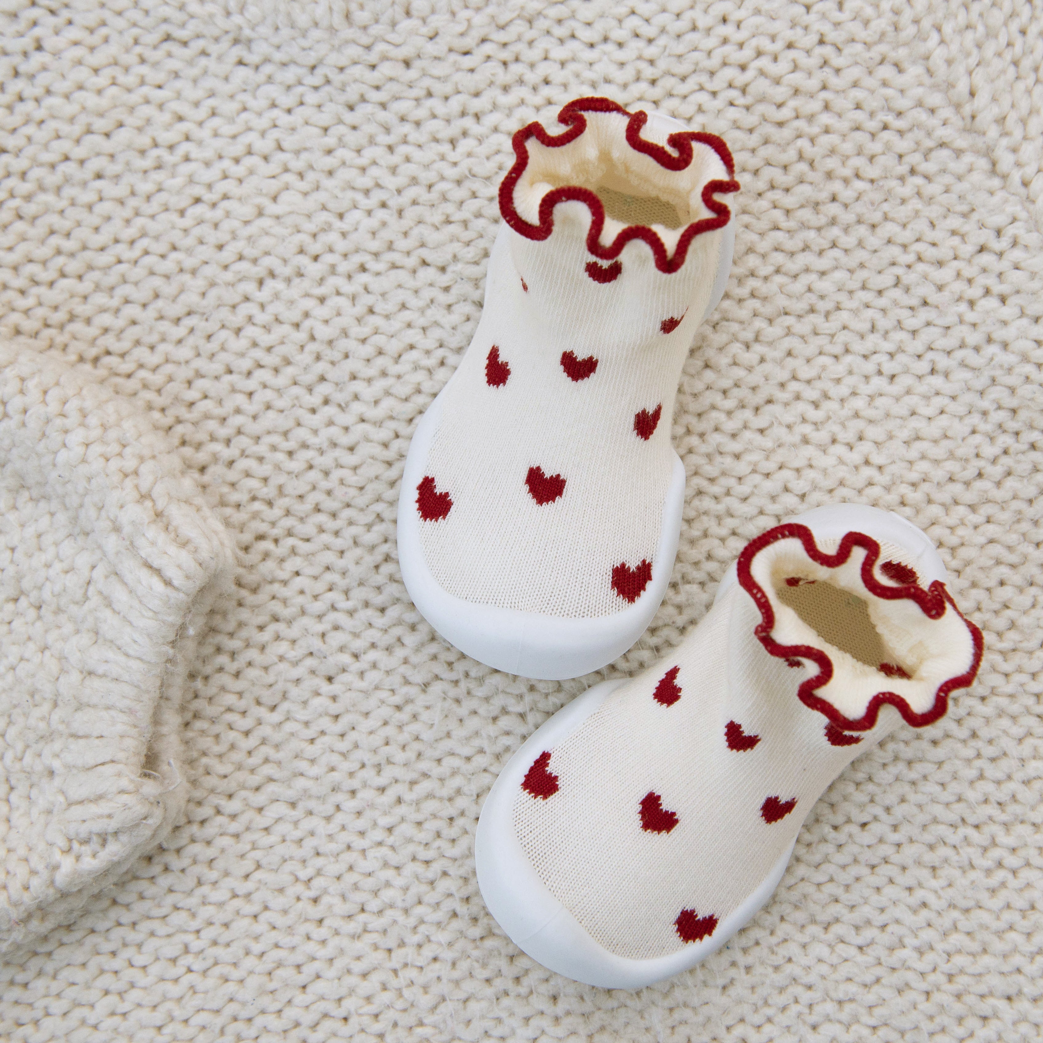 White socks with red heart patterns on a beige textured background