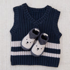 Navy and white striped sweater vest with cartoon shoes on a textured surface
