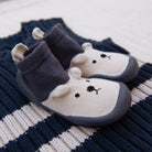 Pair of bear-shaped socks with dark gray soles on a striped fabric background