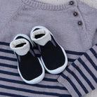 Black and white baby boots on a striped sweater with a gray sweater in the background