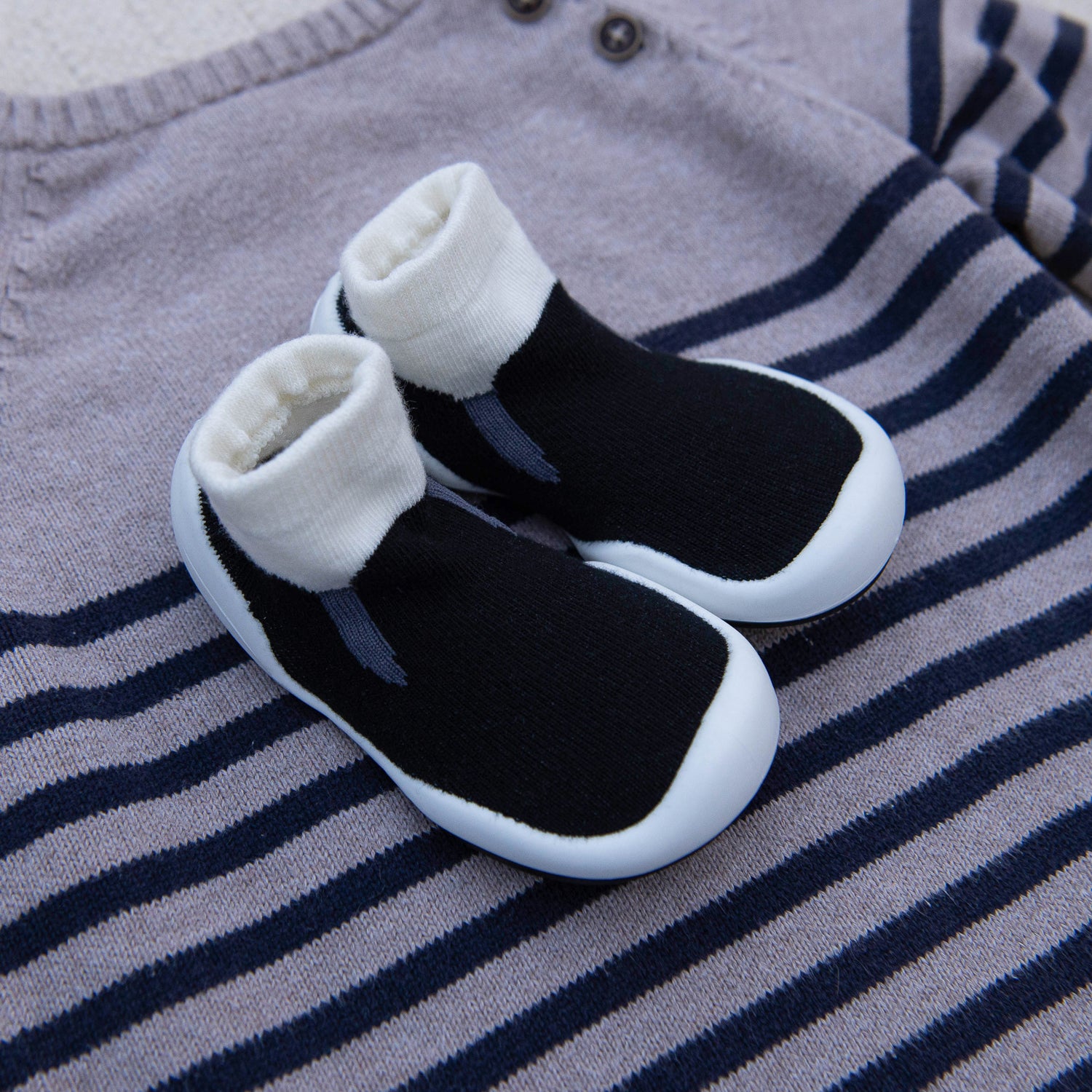 Black and white baby shoes on a striped fabric background