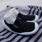 Black and white baby shoes on a striped fabric background