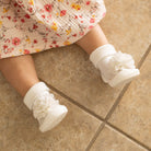 Baby in floral dress with white socks and shoe with flower.