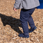 Child wearing navy shoes with white polka dots on a wooden ground
