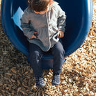 Child sitting on a blue playground tube slide with wood chips below