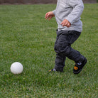 Child playing with a white ball on a grassy field