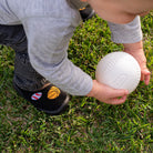 Child holding a white ball on grass