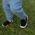 Child wearing black shoes with white soles on grass