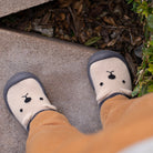 Baby's feet wearing white socks with black details on a concrete surface.