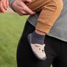 Child's foot wearing a gray sock with a bear design, standing on grass.