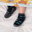 Child wearing socks with a car pattern and gray sock shoes while reading a book.