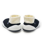 Pair of baby booties with white soles and cream-colored tops on a white background