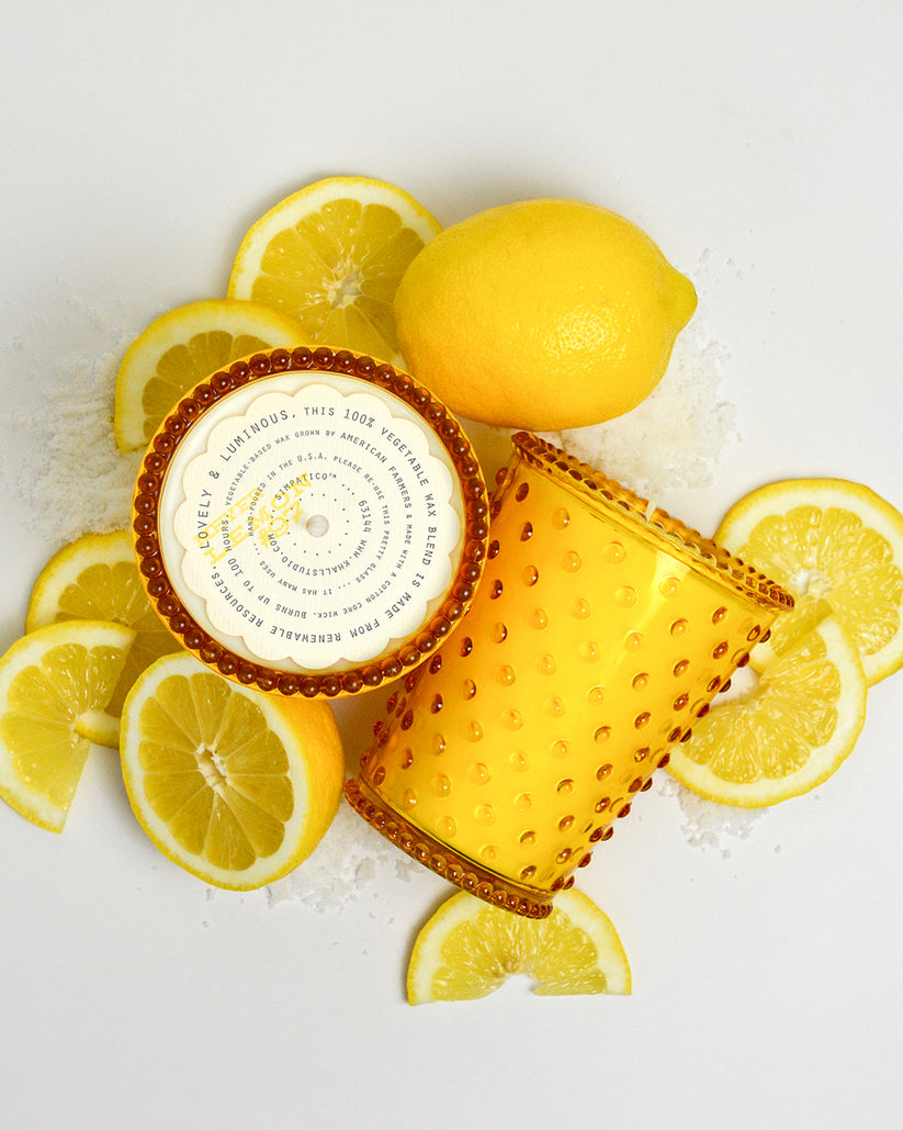 Two amber glass tumblers with a label surrounded by sliced lemons on a white background