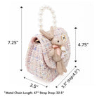 Front view of a tweed purse with a rabbit plushie.