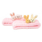 Two pink fuzzy headbands with stuffed animal heads. One headband has a bunny and a teddy bear, the other has two bunnies.