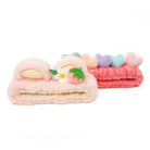 Two fuzzy headbands, one pink with heart decorations and one with a strawberry and flower.