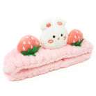 Pink fuzzy headband with white rabbit and strawberry accents.