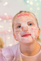 Girl with a sheet face mask. Pink shirt. Bokeh background.