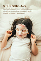 A young girl in a white shirt lies on a striped blanket with a facial mask.