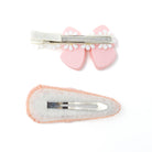 Two hair clips, one pink bow with a white beaded trim and the other a pink and white oval.