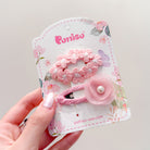 Two pink flower hair clips on a decorative card held in a hand.