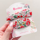 Two floral-patterned hair clips on a decorative card, held by a hand.