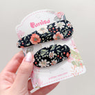 Two floral hair clips on a floral-themed display card.