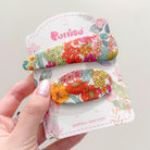 Close-up of floral hair clips on a white display card.