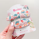 Two floral fabric hair clips on product packaging.