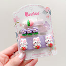 Pack of hair clips on a white card with floral details. Includes one strawberry bear clip, one flower clip, and three bunny clips, each holding a strawberry. All clips are attached to lavender or pink fabric.