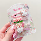 A hand holding a hair clip set with bunnies and flowers on a floral-printed card.